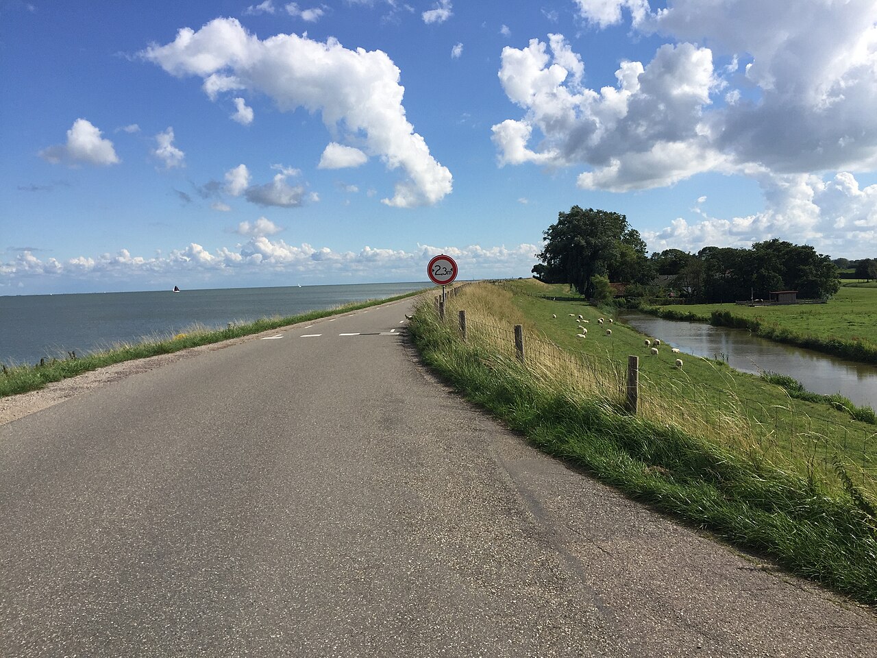 De Westfriese Omringdijk met grasdijk, weg en open polderlandschap.